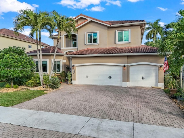 mediterranean / spanish house featuring a tile roof, decorative driveway, and stucco siding