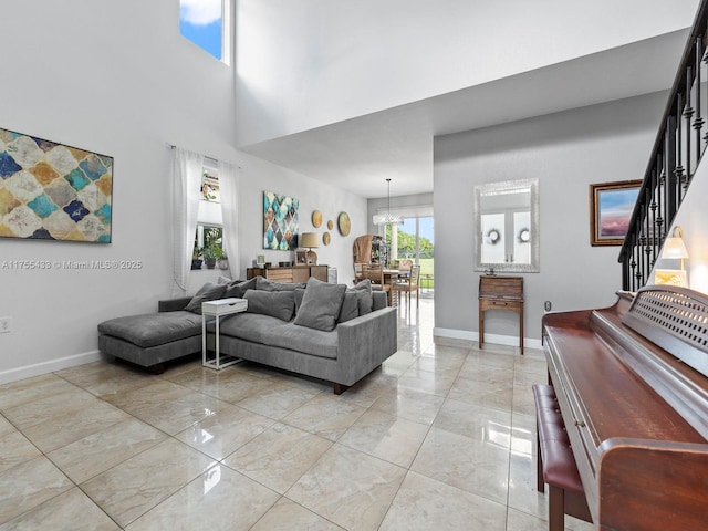 living area with marble finish floor, a notable chandelier, a high ceiling, baseboards, and stairs