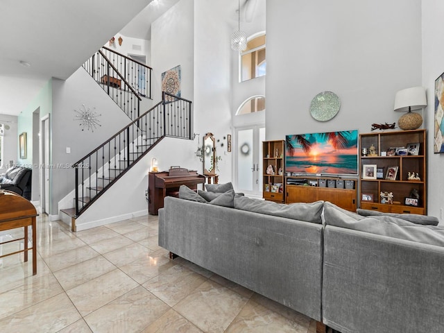 living room featuring marble finish floor, baseboards, a high ceiling, and stairway