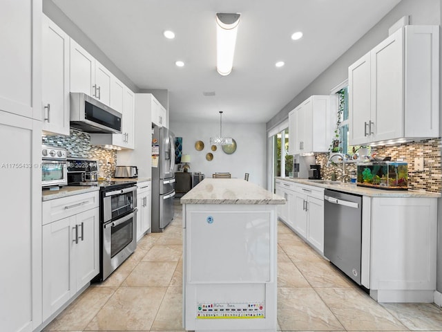 kitchen featuring white cabinetry, a kitchen island, appliances with stainless steel finishes, and a sink