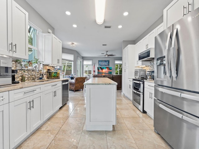 kitchen featuring appliances with stainless steel finishes, a center island, visible vents, and backsplash