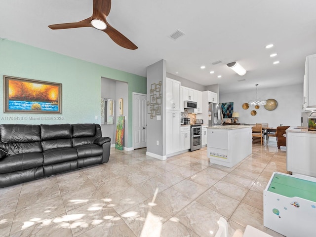 kitchen with stainless steel appliances, a kitchen island, visible vents, white cabinets, and open floor plan