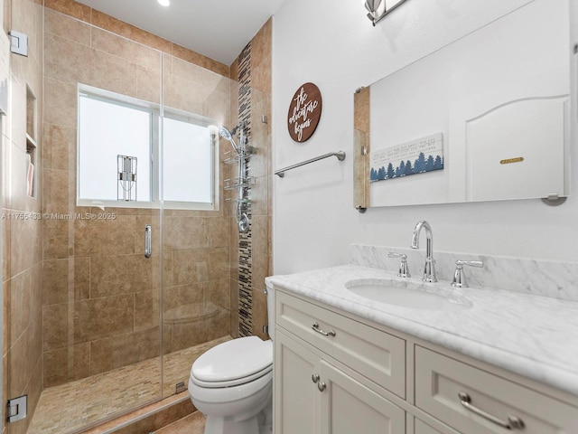 bathroom featuring vanity, a shower stall, and toilet