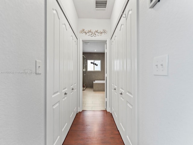 hallway with dark wood-style flooring and visible vents