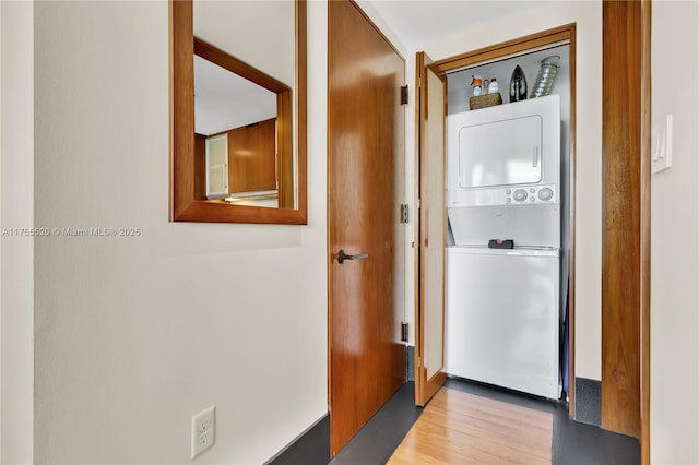 clothes washing area with laundry area, wood finished floors, and stacked washer and clothes dryer