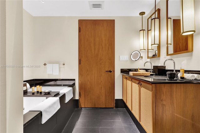 kitchen featuring brown cabinets, dark countertops, visible vents, and dark tile patterned floors