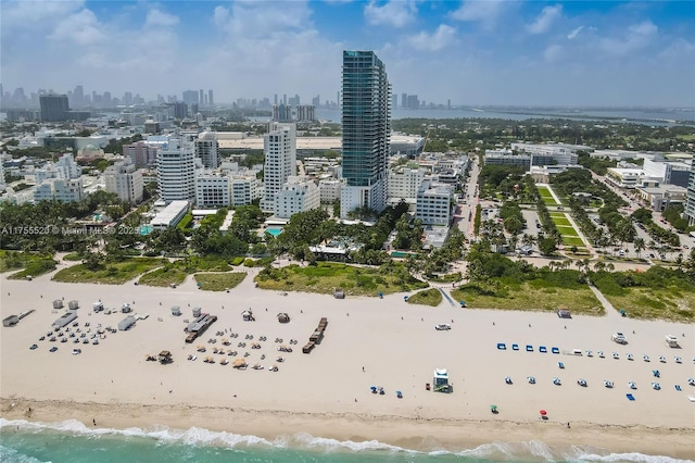 drone / aerial view featuring a view of city, a water view, and a beach view