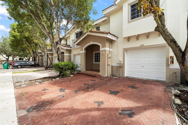 view of front of house with a garage, decorative driveway, a tile roof, and stucco siding