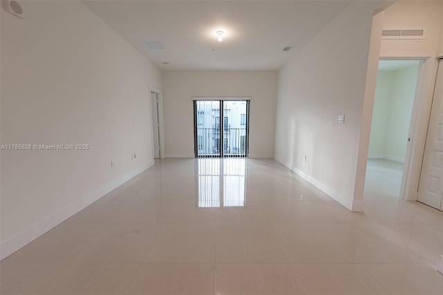 spare room with light tile patterned floors, visible vents, and baseboards