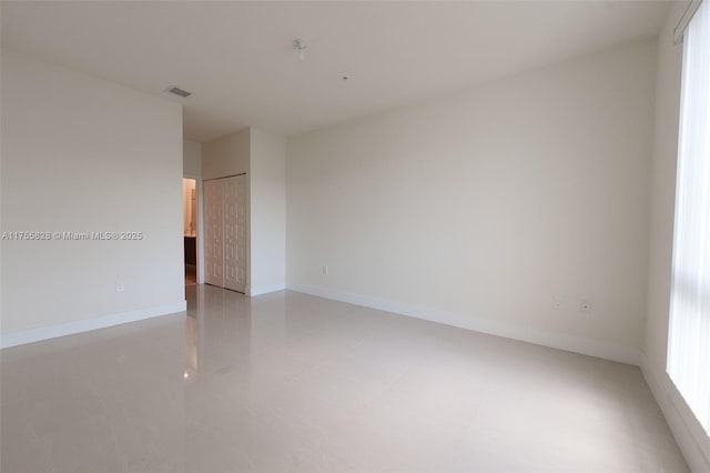 unfurnished room featuring visible vents, plenty of natural light, and baseboards