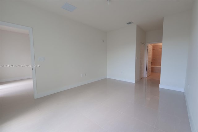 empty room with light tile patterned floors, baseboards, and visible vents