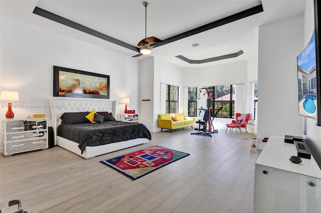 bedroom with a tray ceiling, ceiling fan, and wood finished floors