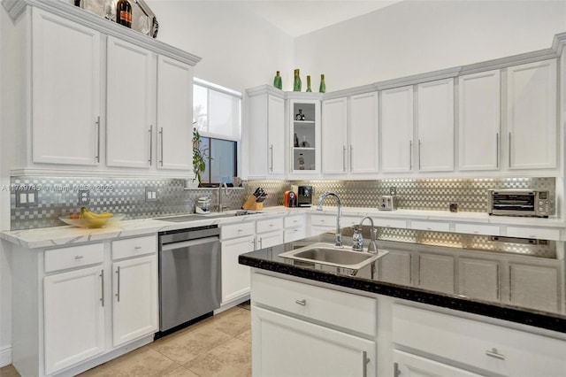 kitchen with stone countertops, a sink, white cabinetry, stainless steel dishwasher, and decorative backsplash