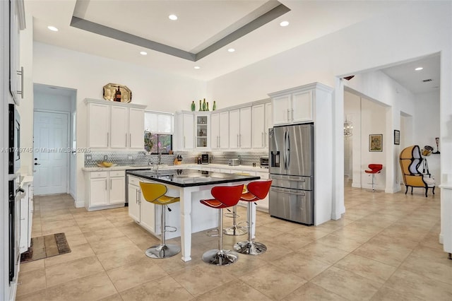 kitchen with white cabinets, a tray ceiling, stainless steel appliances, and a breakfast bar area