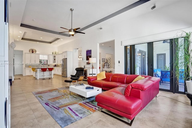 living area with a tray ceiling, french doors, light tile patterned floors, a towering ceiling, and ceiling fan