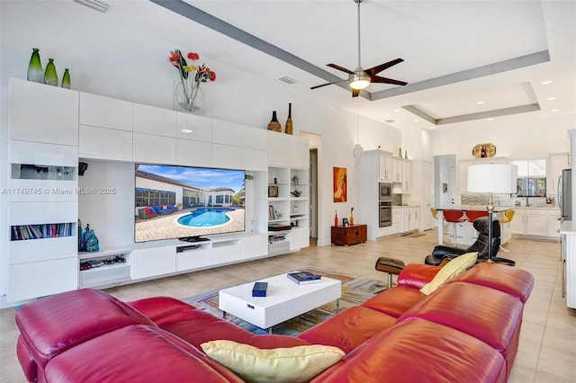 living room with a tray ceiling, recessed lighting, a towering ceiling, a ceiling fan, and light tile patterned flooring