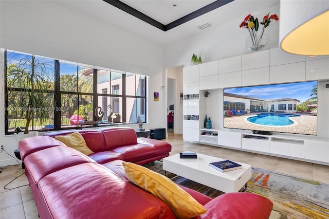 living room featuring a towering ceiling, visible vents, and light tile patterned flooring