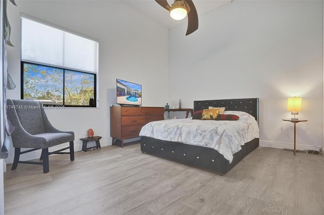 bedroom featuring wood finished floors, a towering ceiling, and baseboards