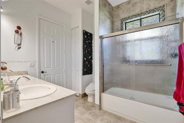 full bath with double vanity, visible vents, toilet, combined bath / shower with glass door, and a sink