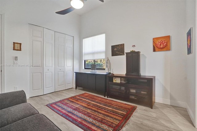 interior space with ceiling fan, wood finished floors, a towering ceiling, and baseboards