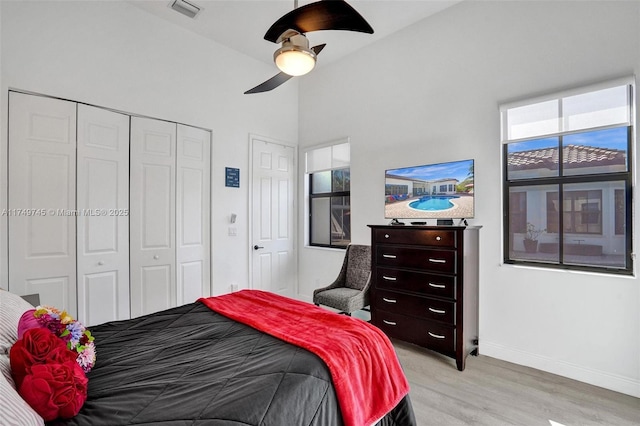 bedroom with a closet, visible vents, light wood-style floors, a ceiling fan, and baseboards