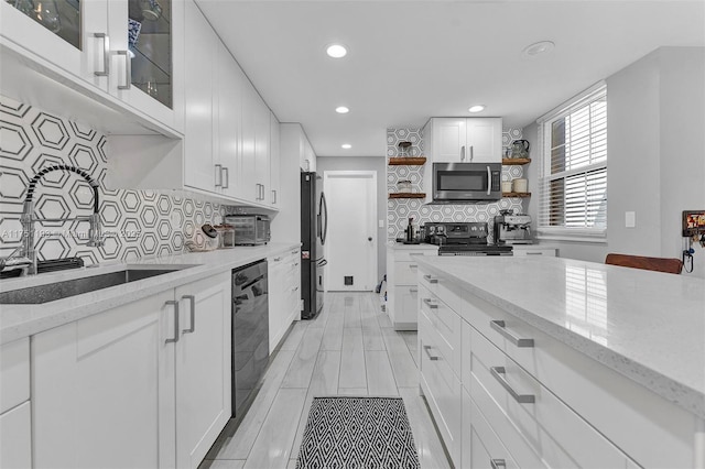 kitchen with open shelves, light stone countertops, white cabinets, and stainless steel appliances