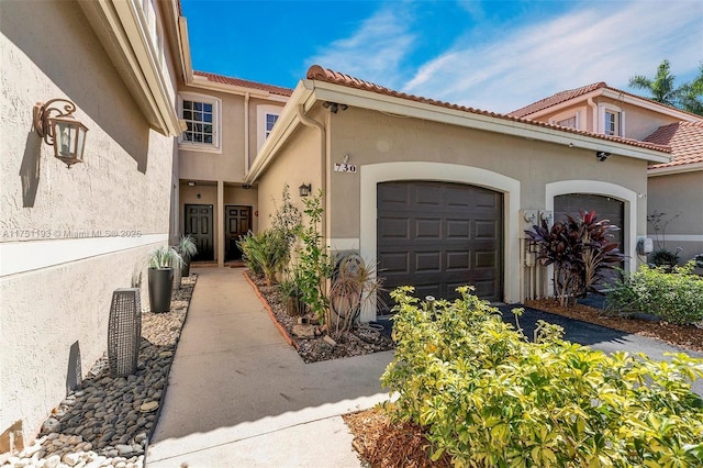 exterior space with a garage, a tiled roof, and stucco siding