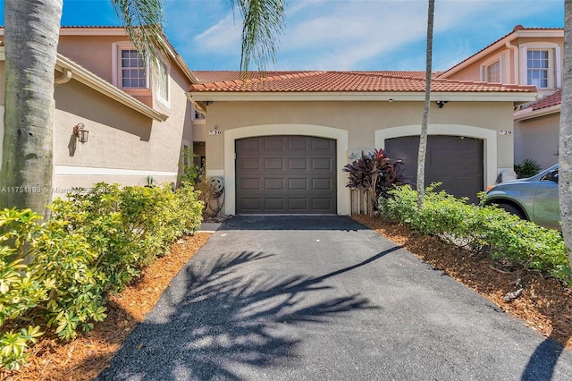 exterior space with an attached garage, driveway, a tile roof, and stucco siding