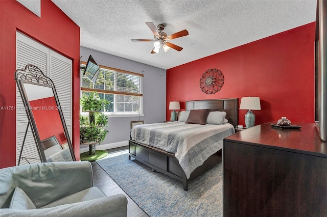 bedroom with a textured ceiling, ceiling fan, wood finished floors, and baseboards