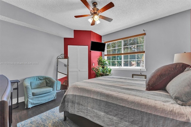 bedroom with a closet, ceiling fan, a textured ceiling, wood finished floors, and baseboards