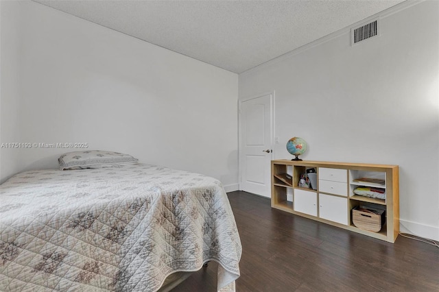 bedroom with visible vents, a textured ceiling, baseboards, and wood finished floors