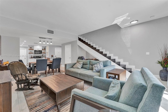 living room featuring stairs, rail lighting, and visible vents