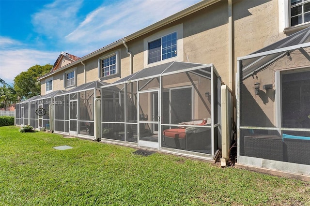 back of house with a lanai, a lawn, and stucco siding