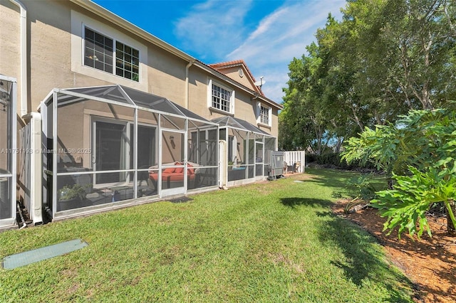 back of house with a yard, glass enclosure, and stucco siding