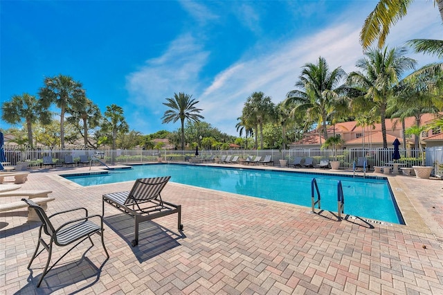 community pool with a patio area and fence