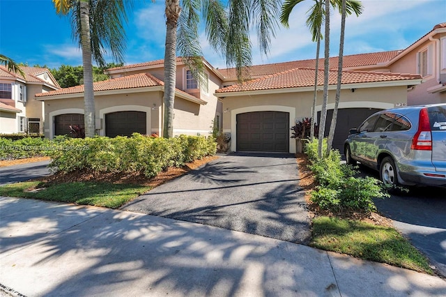 mediterranean / spanish-style home with aphalt driveway, a garage, and stucco siding