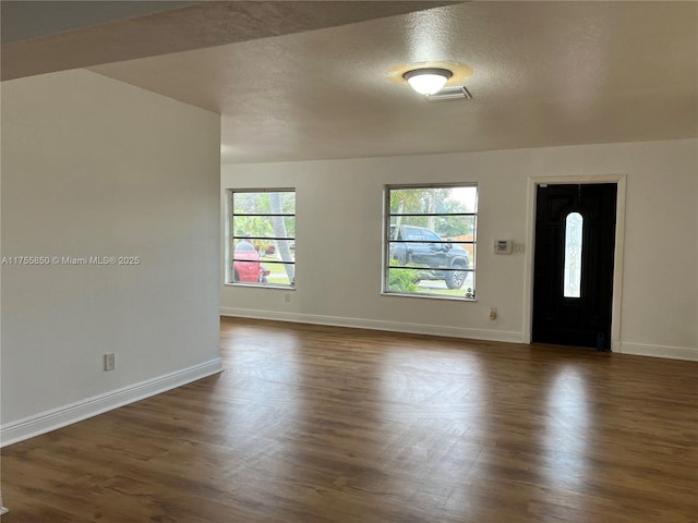 foyer featuring baseboards and dark wood-type flooring