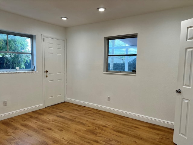 unfurnished room featuring plenty of natural light, baseboards, and wood finished floors