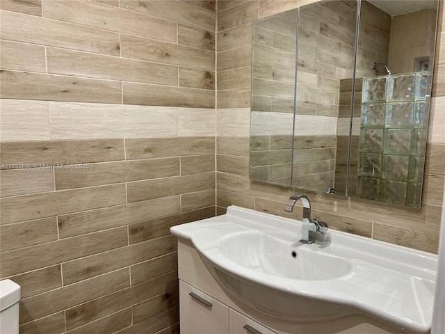 full bath with a tile shower, vanity, and toilet