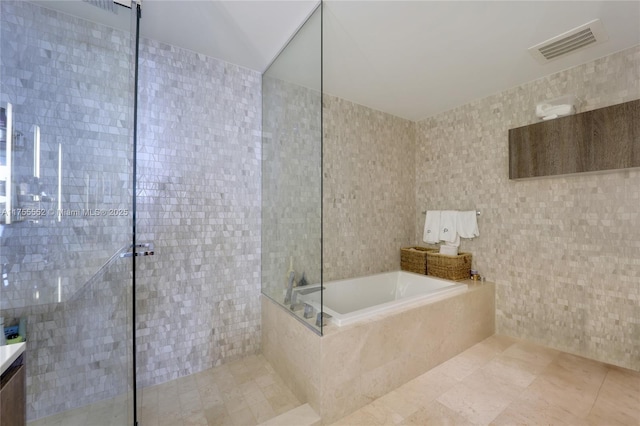 bathroom featuring a garden tub, visible vents, a tile shower, vanity, and tile patterned floors