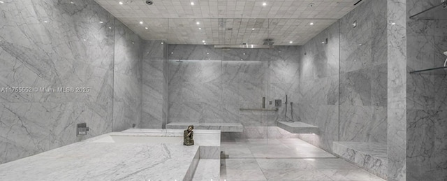 bathroom featuring a marble finish shower, tile walls, and recessed lighting