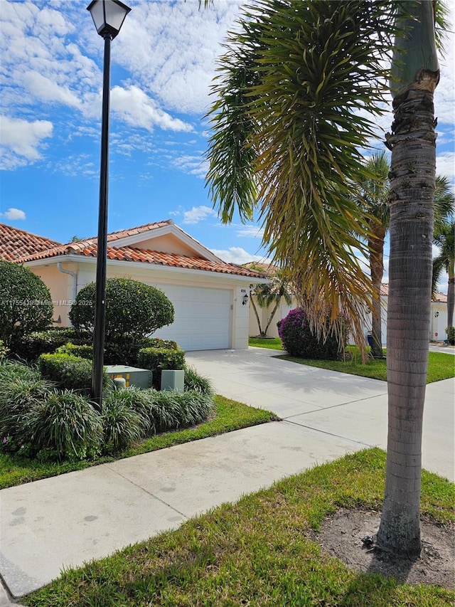 view of front of property featuring driveway, a tiled roof, and an attached garage