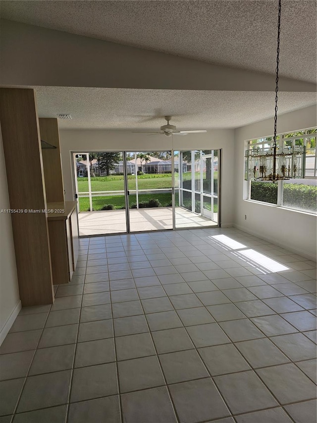 spare room featuring a ceiling fan, light tile patterned flooring, visible vents, and a textured ceiling