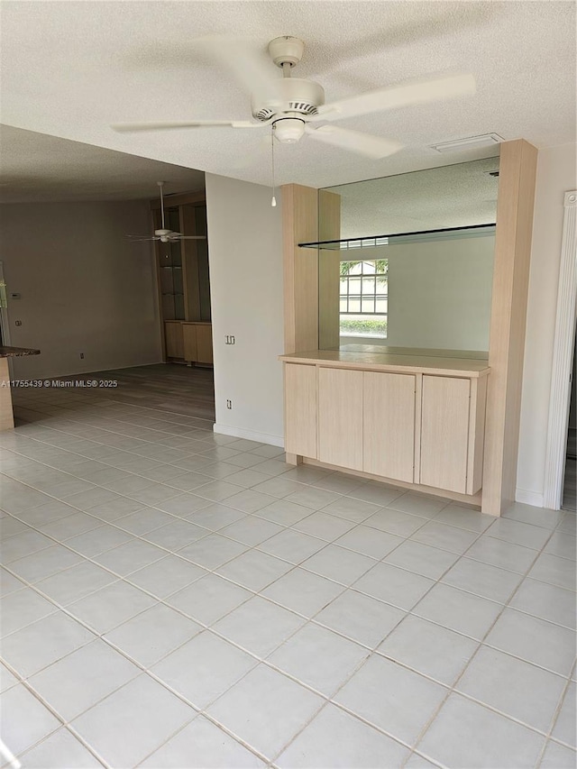 empty room featuring a ceiling fan, a textured ceiling, and light tile patterned floors