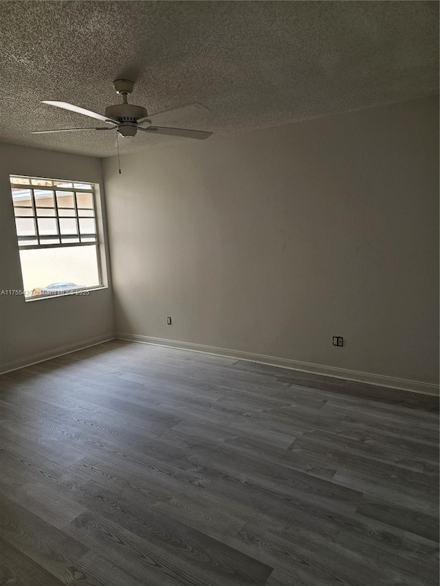 spare room with a ceiling fan, dark wood finished floors, a textured ceiling, and baseboards