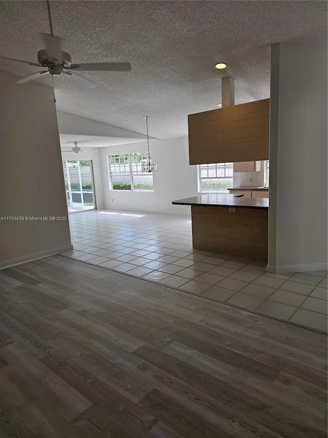 kitchen featuring a wealth of natural light, open floor plan, a textured ceiling, and wood finished floors