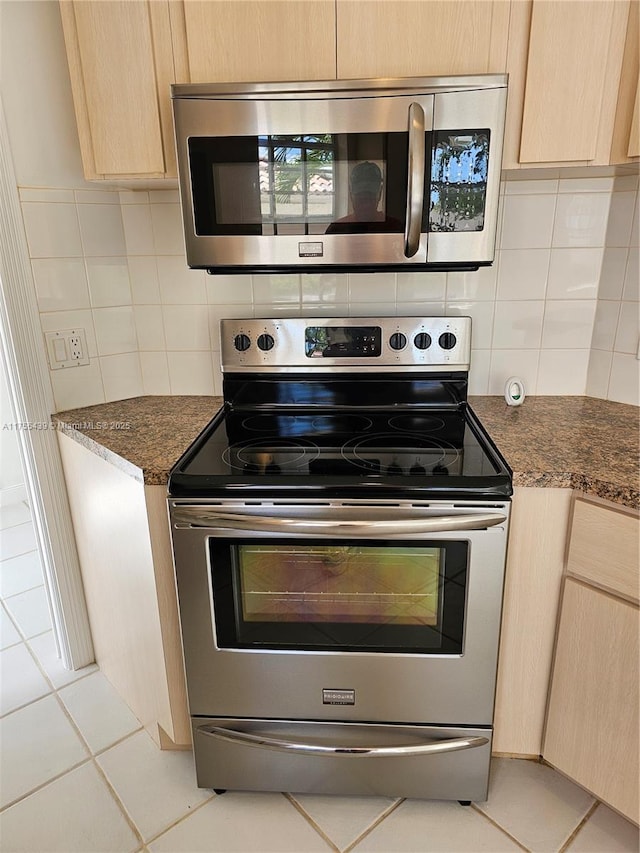 kitchen with light tile patterned floors, light brown cabinets, appliances with stainless steel finishes, and decorative backsplash