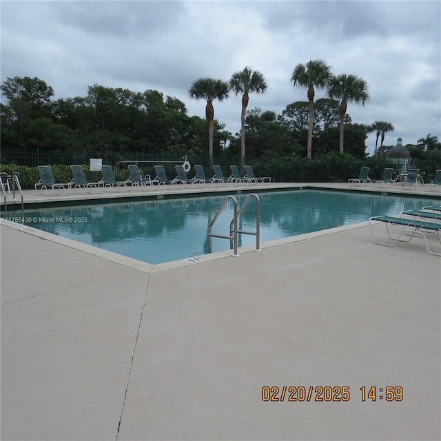 pool with a patio area and fence