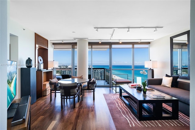 living room featuring a water view, expansive windows, track lighting, and dark wood-style flooring