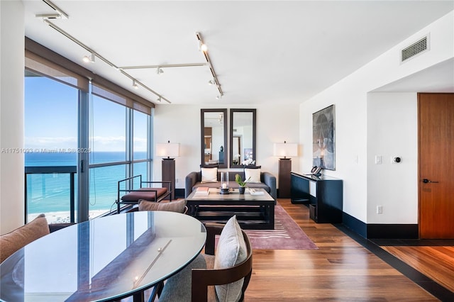 dining room with a water view, wood finished floors, visible vents, and track lighting